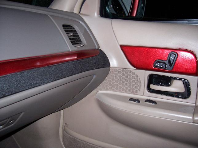 Close-up of a car's interior door panel, showing the armrest, seat controls, and speaker grille