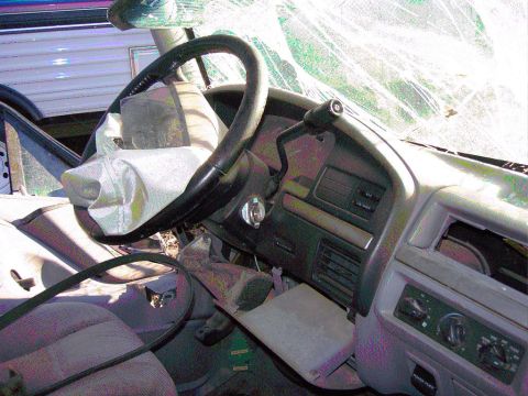 1981 Ford F-150 - The interior of a damaged truck shows a deployed airbag and a shattered windshield.