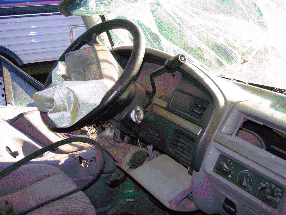 Truck interior with deployed airbag and cracked windshield