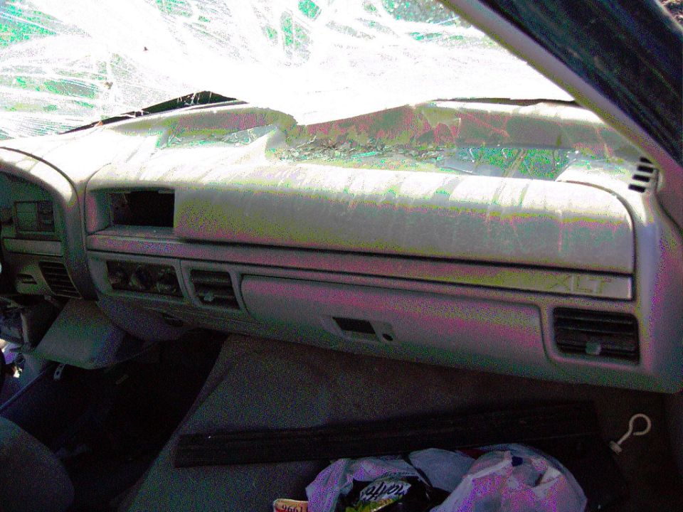 Dashboard of a damaged 1992 Ford F-150, showing cracked windshield and worn interior