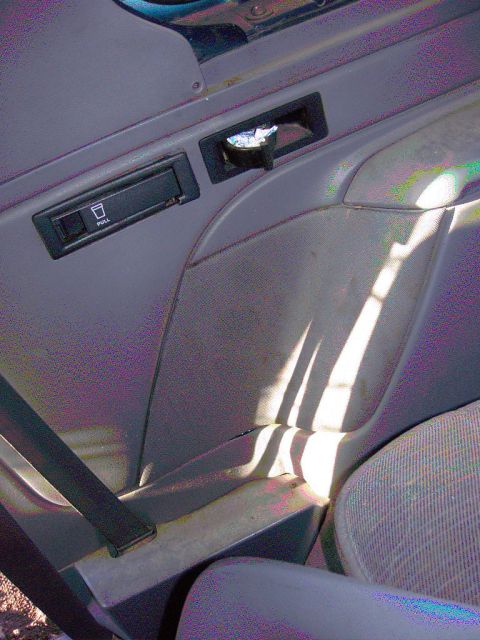 1981 Ford F-150 - Interior view of a car door panel with a cup holder and pull handle.
