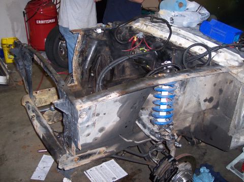 1967 Ford Mustang - The engine bay of a 1967 Ford Mustang shows a disassembled front end with a blue coilover suspension system visible.