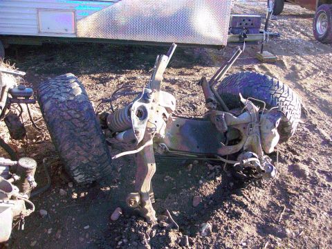1981 Ford F-150 - Front axle and suspension parts from a truck are scattered on the ground.
