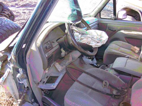 1981 Ford F-150 - Interior of a wrecked pickup truck shot through the missing driver's door, showing a deployed driver's airbag draped over the steering whee…