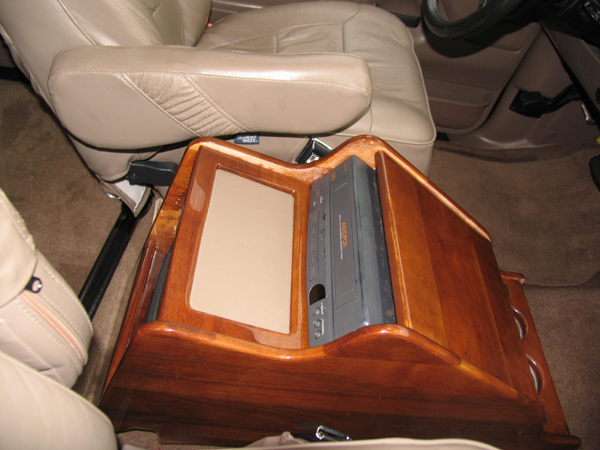 Custom wood center console between tan leather bucket seats in a conversion truck