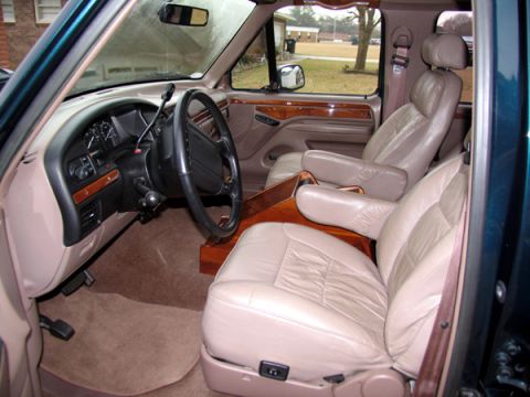 1995 Ford C-150 (Centurion Conversions) - The interior of the van shows plush tan leather seats, a wood-trimmed dashboard, and a steering wheel.