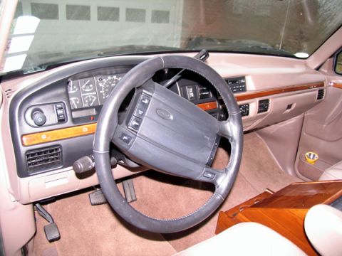 1995 Ford C-150 (Centurion Conversions) - The interior of a 1995 Ford C-150 Centurion Conversions features a tan dashboard, wood accents, and a prominent steering wheel.