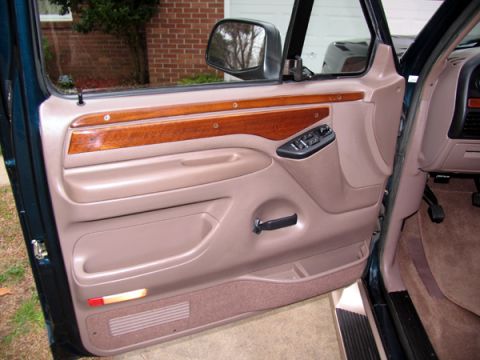 1995 Ford C-150 (Centurion Conversions) - Interior view of the driver's side door panel, showing wood grain trim and power controls.
