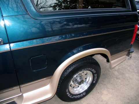 1995 Ford C-150 (Centurion Conversions) - The rear quarter panel and wheel of a Ford Bronco are shown, a two-tone paint scheme and chrome accents.