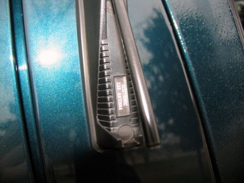 1995 Ford C-150 (Centurion Conversions) - Close-up of a car's fender showing the base of an electronic antenna.