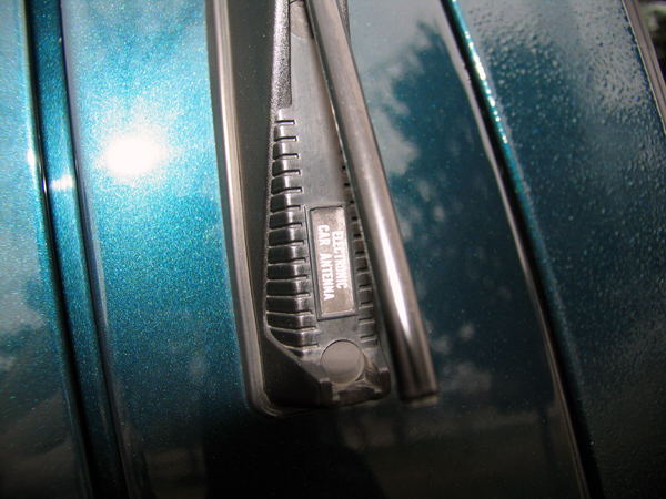 Teal metallic car fender with black electronic car antenna base