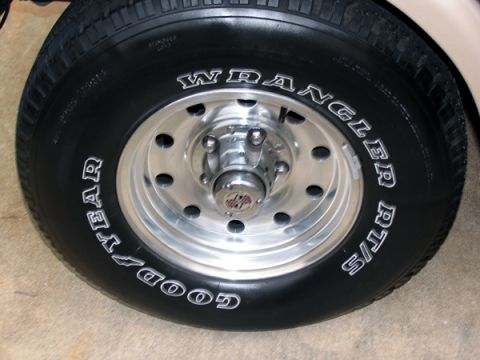 1995 Ford C-150 (Centurion Conversions) - A detailed view of a Goodyear Wrangler RT/S tire mounted on a polished chrome wheel.