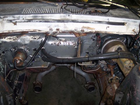 1967 Ford Mustang - Firewall and exhaust manifolds in a vehicle's engine bay, showing signs of wear and tear.