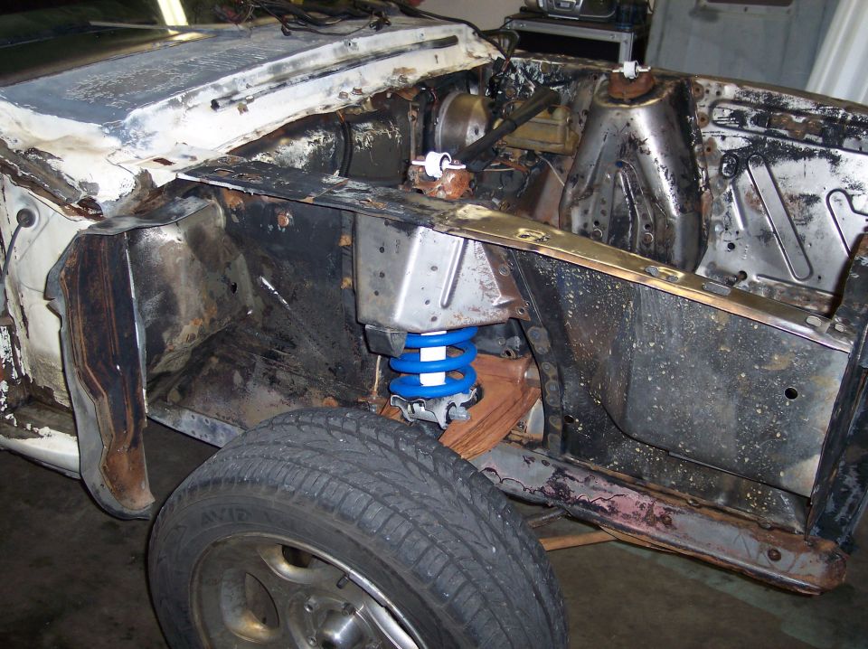 1967 Ford Mustang engine bay with blue coilover suspension and rust