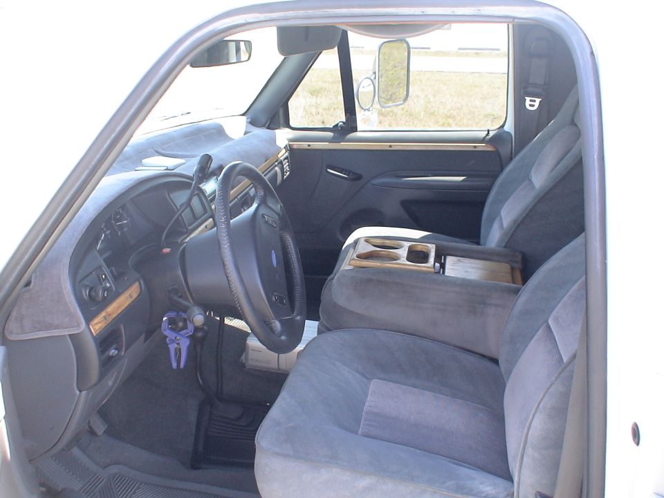 Gray cloth front interior of a Ford truck with woodgrain console and dash trim
