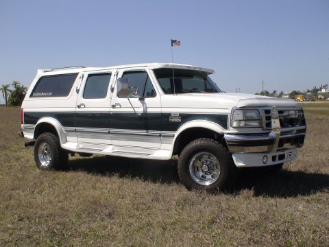 1993 Ford C-350 (Centurion Conversions) - White Ford C-350 Centurion Conversion van with dark green stripe, parked on grass under a clear blue sky.