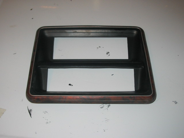 Dashboard trim piece with wood grain accent and two rectangular openings