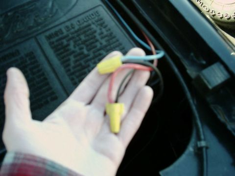 1984 Ford Bronco - Close-up of a hand holding wire connectors, likely for a headlight rewire.