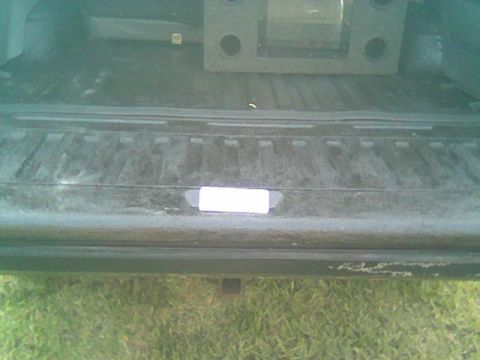 1992 Ford Bronco - The interior of a truck bed is shown, containing a subwoofer box and a sticker on the tailgate.