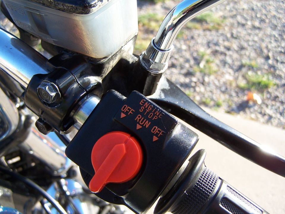 Close-up of motorcycle handlebar with engine stop switch and brake lever