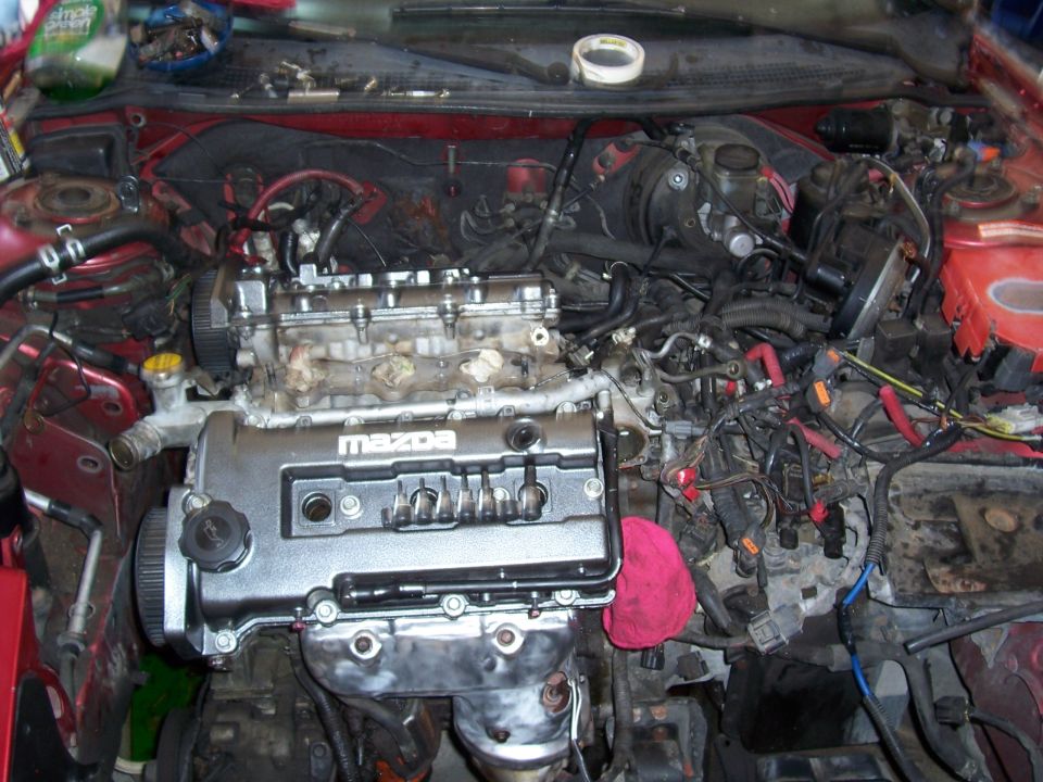 Engine bay with Mazda engine cover, wires, and hoses visible