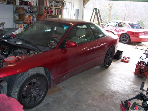 1996 Ford Probe - A red 1996 Ford Probe coupe sits in a garage with its hood open, while another red car is visible in the background.