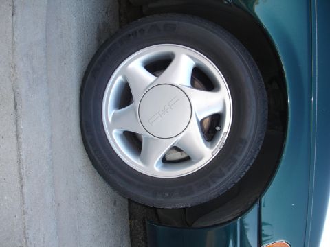 1995 Ford Taurus - A close-up view of a car's wheel, a five-spoke design and a center cap with 'PKE' branding.