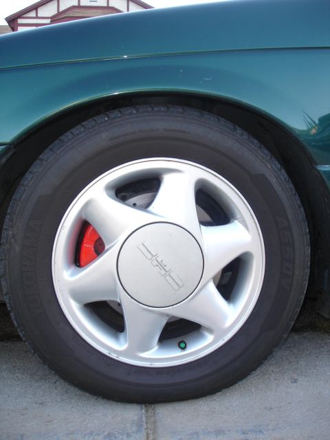 1995 Ford Taurus - A close-up view of a vehicle's wheel and fender, showing the tire and brake caliper.