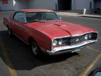 1972 Ford Ranchero - 1970 Ford Torino GT coupe with a hood scoop and distinctive grille, parked in a lot.