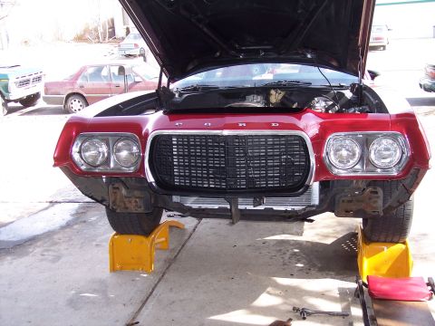 1972 Ford Ranchero - Front view of a red 1972 Ford Ranchero undergoing repairs, with its hood raised and front wheels supported.