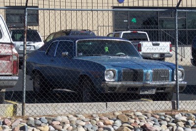 1972 Ford Ranchero - A blue coupe with a distinctive grille is parked behind a chain-link fence.
