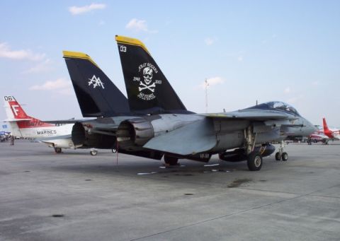 1998 Ford Crown Victoria - A fighter jet with "Jolly Rogers" markings is parked on an airfield next to another aircraft.