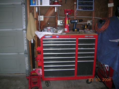 1985 Ford Bronco - A red Craftsman tool chest sits in a garage, holding various car parts and tools, with a garage door in the background.