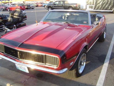 1979 Ford Bronco - A red 1968 Chevrolet Camaro convertible is parked in a lot with other vehicles and a motorcycle.