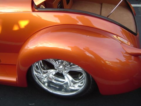 1979 Ford Bronco - Close-up of a custom hot rod's rear fender and wheel, showing its bright orange paint and custom interior.