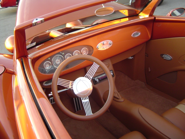 Orange hot rod interior with tan leather seats and a chrome-spoked steering wheel