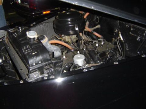 1979 Ford Bronco - Engine bay of a black vehicle, showing the radiator and carburetor. Another vehicle is visible in the background.