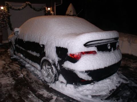 1996 Ford Probe - A black coupe is parked outside and covered in a thick layer of snow during a winter night.