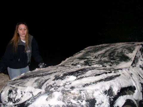 1996 Ford Probe - A woman clears snow from a car's windshield during a winter night.