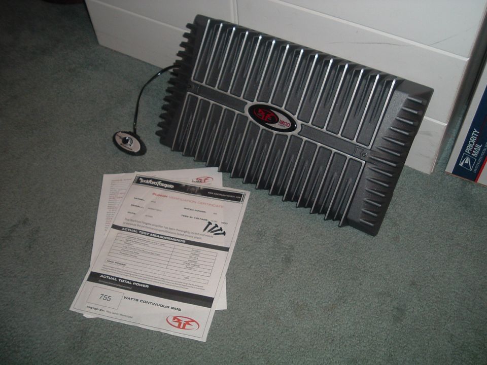 Rockford Fosgate Punch car amplifier on carpet with its spec sheet and mounting screws