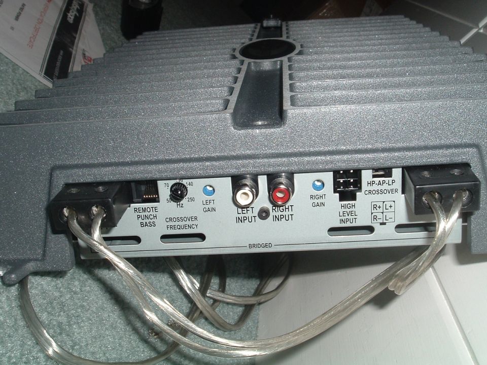 Gray car audio amplifier end panel with RCA inputs, gain knobs and speaker terminals