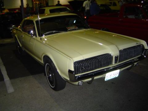1979 Ford Bronco - This yellow 1969 Mercury Cougar XR7 is parked outdoors at night with other vehicles nearby.