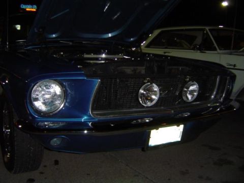 1979 Ford Bronco - Front end of a blue classic Mustang, hood up, with another car visible behind it.