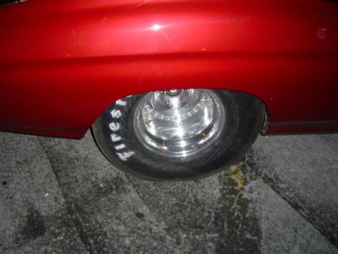 1979 Ford Bronco - Close-up of a red car's rear fender and wheel with custom chrome rims and racing tires.