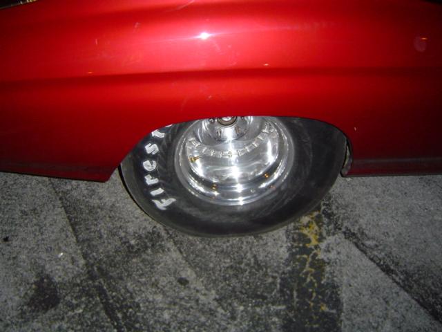 Red car fender over a chrome wheel with Firestone tires
