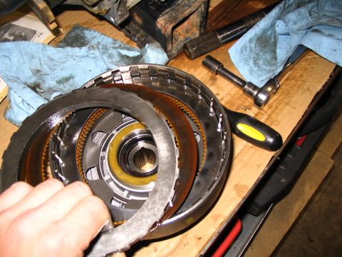1984 Ford Bronco - Disassembled automatic transmission torque converter components are laid out on a workbench with tools.