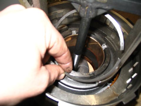 1984 Ford Bronco - Close-up of a hand manipulating a part within a transmission assembly.