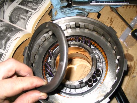 1984 Ford Bronco - A close-up view of internal transmission components, including springs and clutch plates, with a service manual nearby.