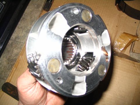1984 Ford Bronco - A hand holds a complex metal gear assembly, likely part of a vehicle's transmission system.