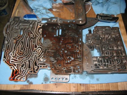1984 Ford Bronco - Close-up of a disassembled automatic transmission valve body, showing its complex internal channels and hydraulic passages.